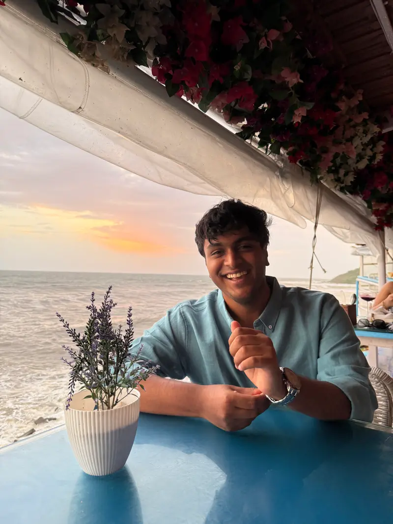 Dev smiling at a seaside table
